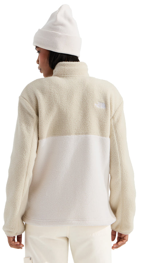 A person viewed from behind wearing a cream-colored knit beanie and a two-toned, textured fleece pullover jacket with a high collar and long sleeves, showing a lighter cream section at the bottom and a slightly darker textured section at the top.