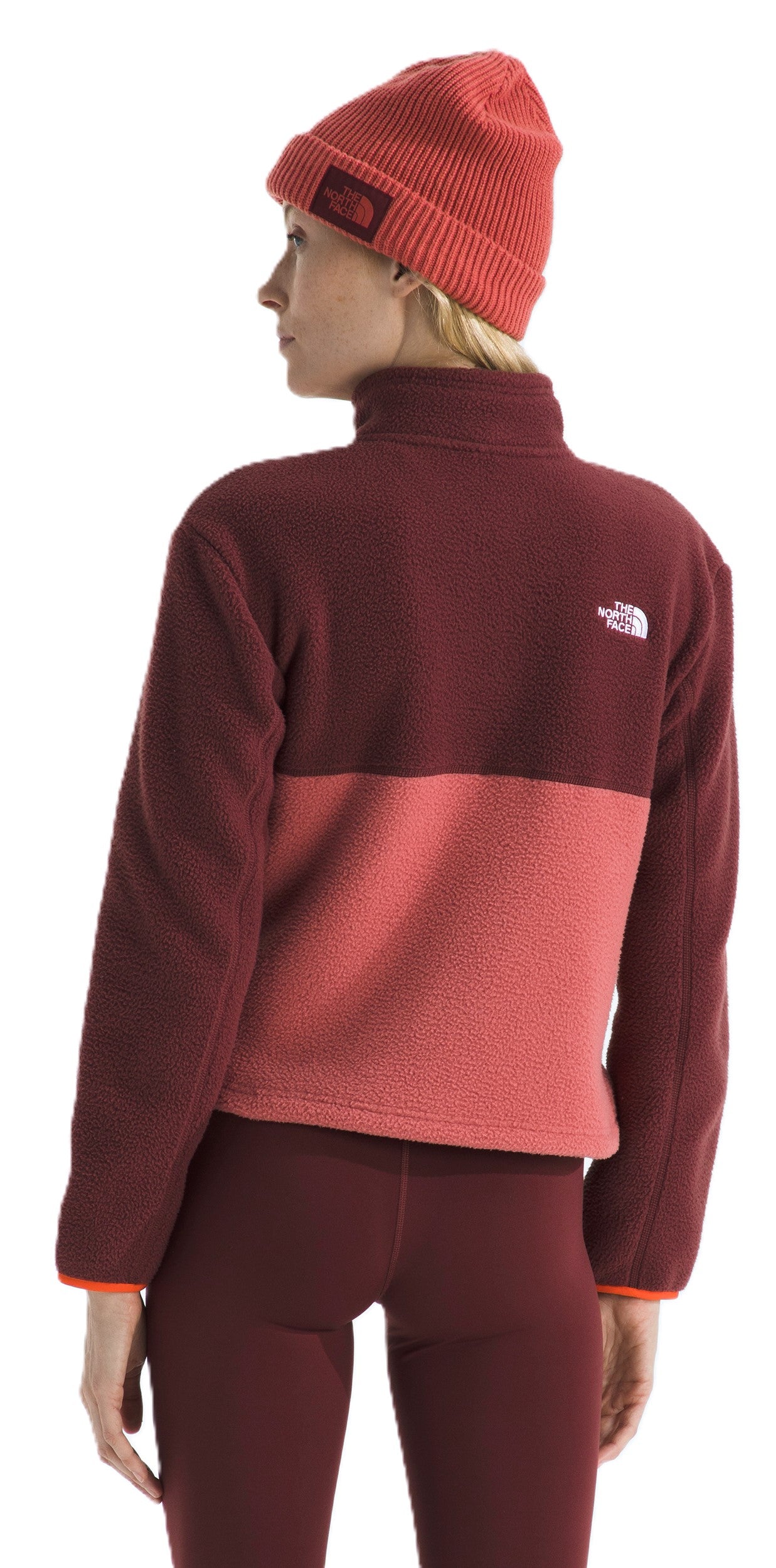 A person wearing a burgundy and pink fleece jacket, burgundy leggings, and a matching beanie.