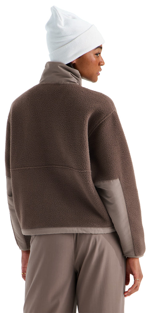 A person viewed from the back wearing a white beanie and a brown fleece jacket with high collar and smooth-textured sleeves, paired with matching brown trousers.