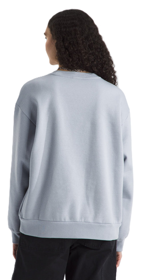 A person with dark curly hair wearing a light blue crew neck sweatshirt and black pants, viewed from the back.