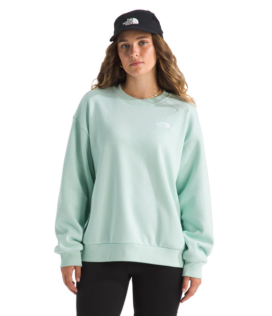 Woman wearing a light green sweatshirt and black cap.