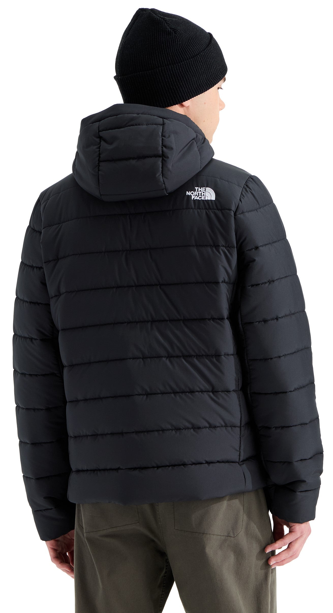 A back view of a person wearing a black quilted puffer jacket with a hood and a black beanie, with the text The North Face visible on the back right shoulder.