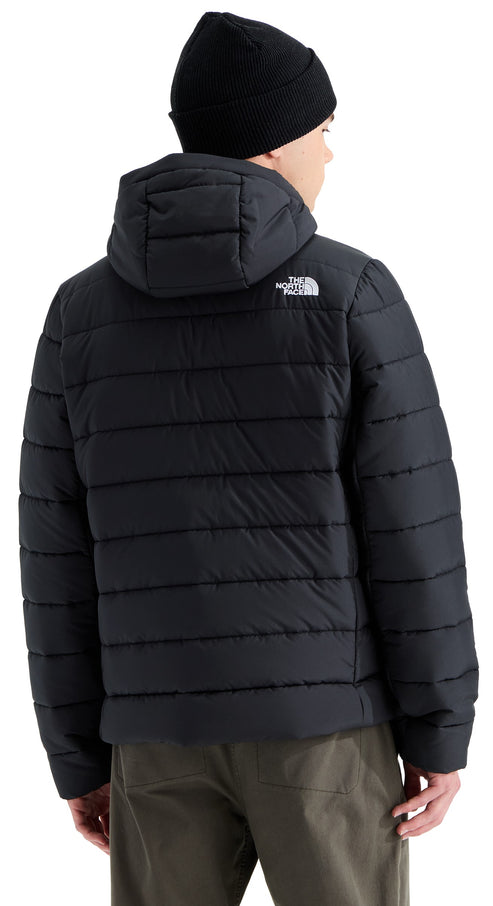 A back view of a person wearing a black quilted puffer jacket with a hood and a black beanie, with the text The North Face visible on the back right shoulder.