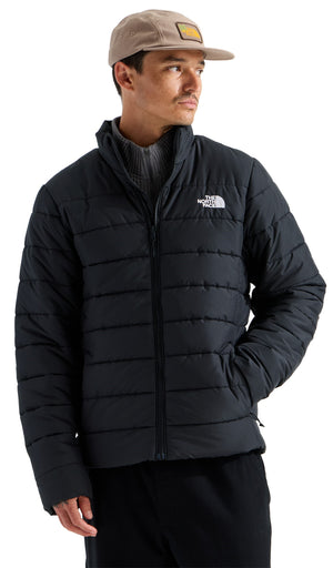 A man wearing a tan baseball cap with a square patch, a grey mock-neck sweater, and a black puffer jacket with horizontal quilting and the white The North Face logo on the chest.