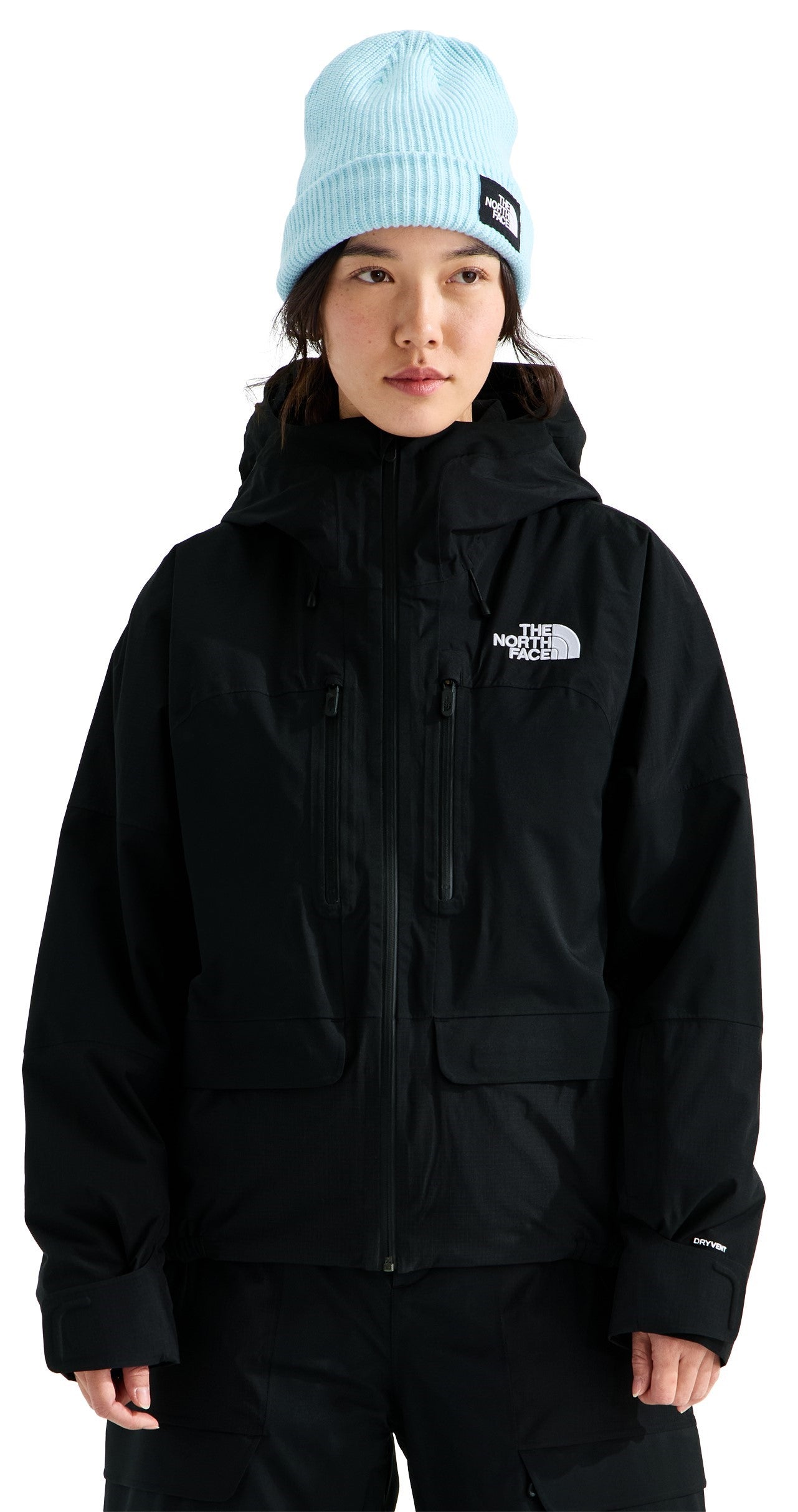 A person wearing a black, zip-up hooded jacket with a front zippered pocket and a light blue knit beanie with a small logo patch.
