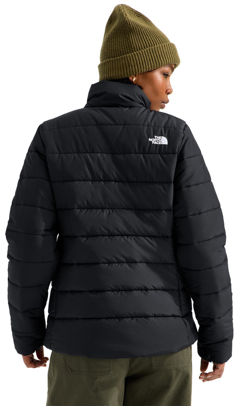 A back view of a person wearing an olive green beanie and a black, horizontal-quilted puffer jacket with the brand logo embroidered in white on the upper right back.