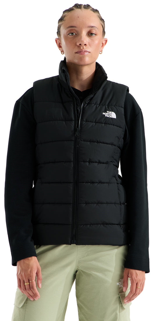 A person wearing a black quilted puffer vest over a black long-sleeved shirt and light sage green cargo pants with The North Face logo visible on the upper left chest.