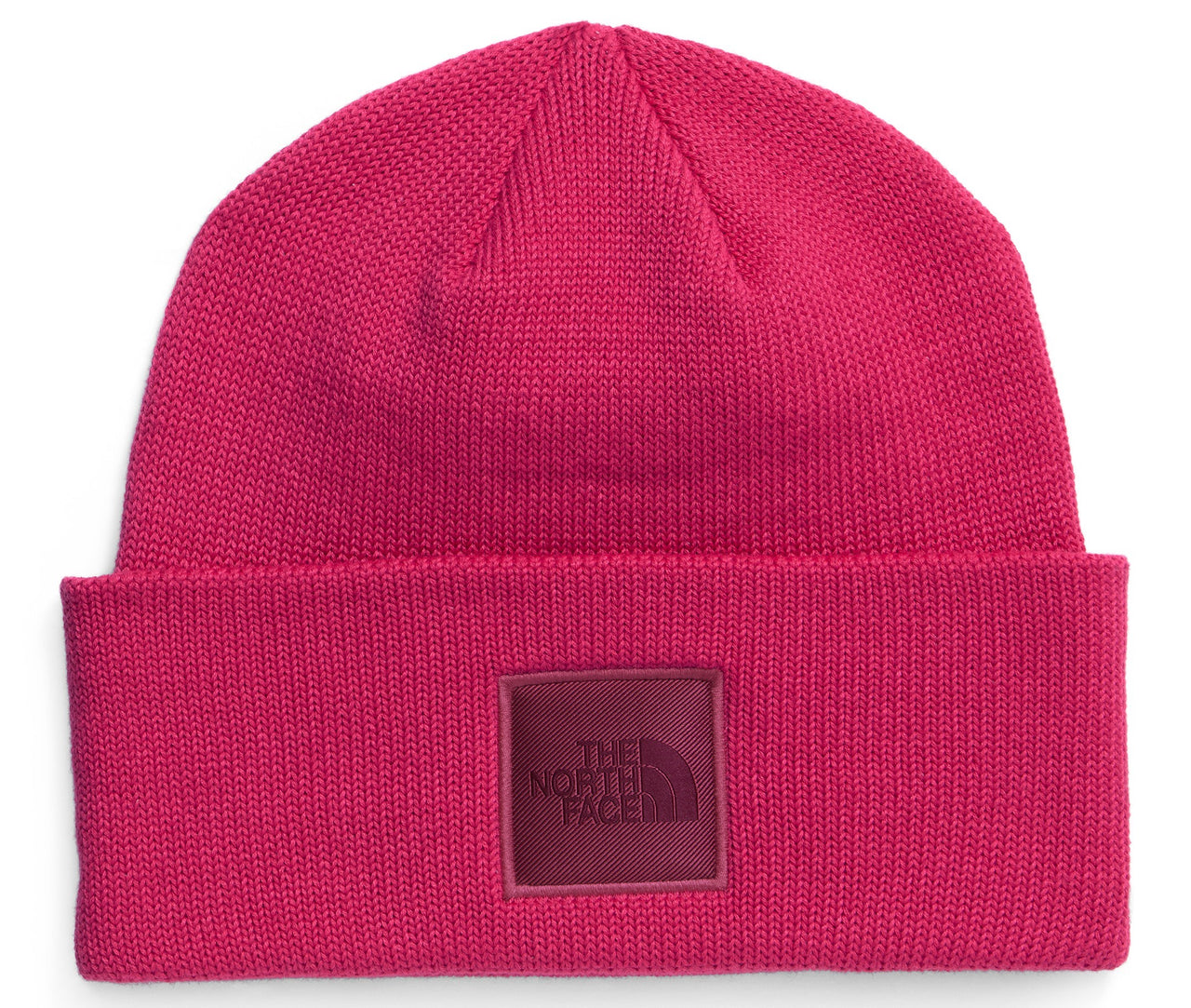 A bright fuchsia knit beanie with a folded cuff and a square patch on the front featuring the text THE NORTH FACE.