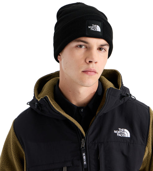 A man wearing a black beanie with The North Face logo and a black and olive green fleece hooded jacket with The North Face logo on the chest.