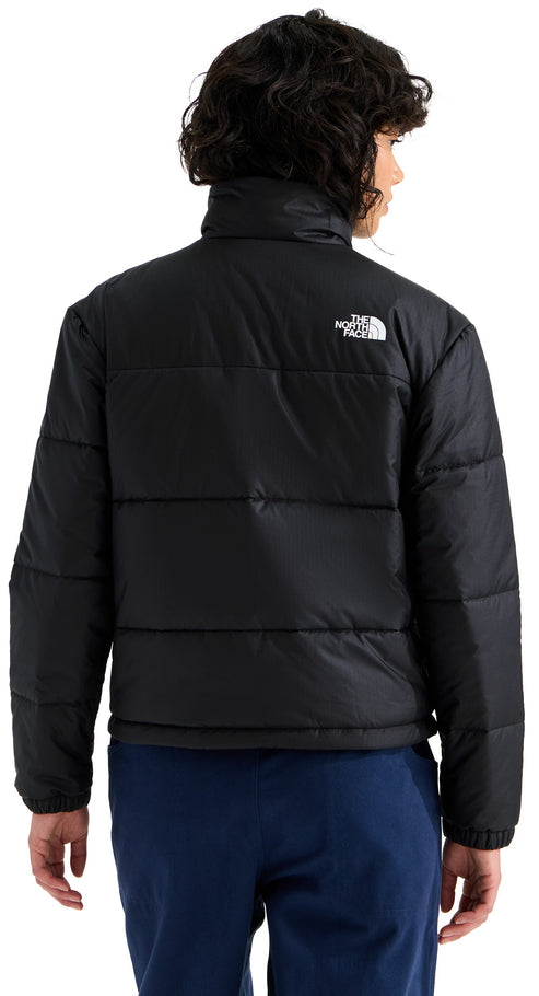 A back view of a person wearing a black, long-sleeved, high-neck puffer jacket with horizontal quilting and the white logo of The North Face on the upper back.