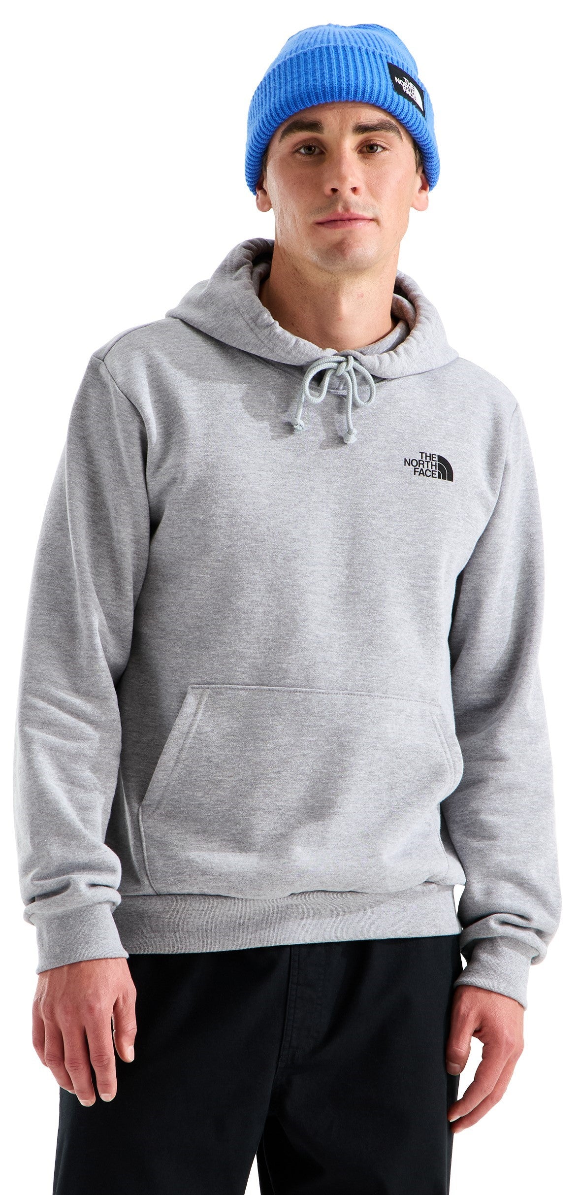 A man wearing a grey hooded sweatshirt with a kangaroo pocket and a light blue knit beanie, styled with a small logo on the chest and a patch on the beanie.