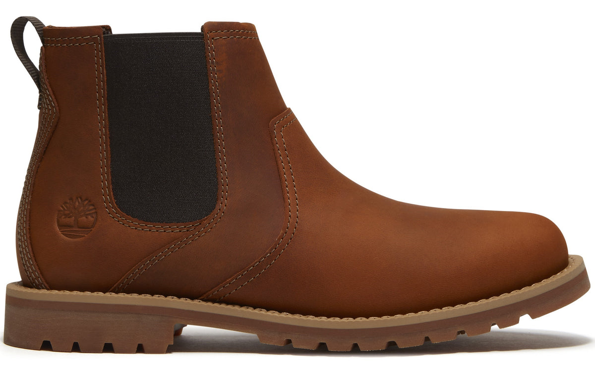 A brown leather Chelsea boot with a round toe, elastic side panel, pull tab at the heel, and a thick, lugged tan rubber sole with visible Timberland logo embossing on the heel.