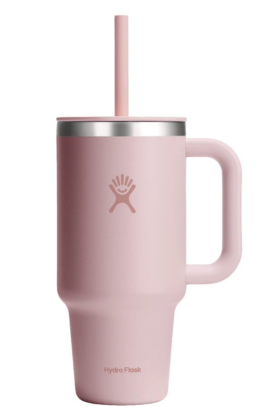 A light pink insulated cup with a handle, straw, and visible text "Hydro Flask".