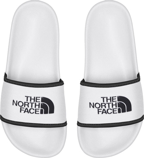 A pair of white slides with black text saying THE NORTH FACE and a black logo.