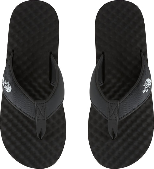 Overhead shot of a pair of black flip-flops with white logo on the strap.