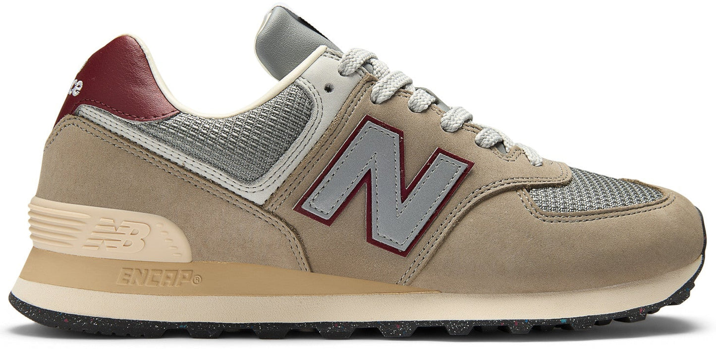 A tan and grey New Balance 574 sneaker with a red heel and a grey 'N' logo.