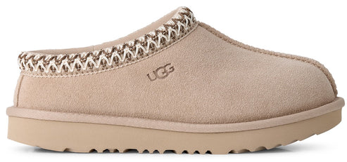 A light tan suede slip-on shoe with a thick rubber sole and a braided decorative trim around the collar, featuring the embossed text UGG on the side.