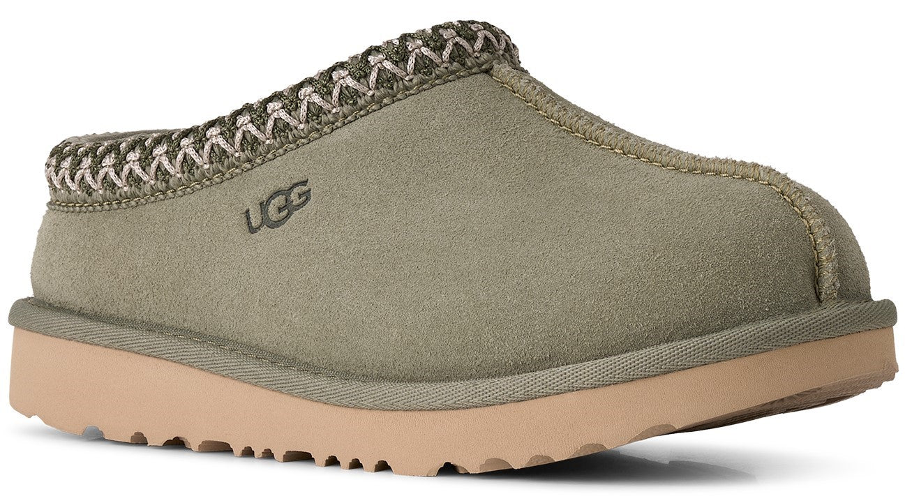 A slip-on shoe with an olive-green suede upper, featuring a decorative braided fabric trim around the collar and a visible UGG logo embossed on the side, set on a thick, light tan platform sole with a textured tread.