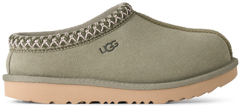 A sage green suede slipper with a woven, cream-colored stitched trim around the collar, featuring the embossed brand name UGG on the side and a flat, light tan rubber sole.