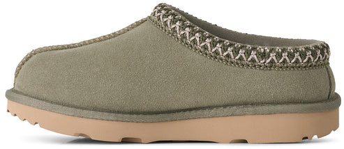 A sage green suede slipper with a thick, tan rubber sole and a decorative braided trim around the collar, viewed from the side.