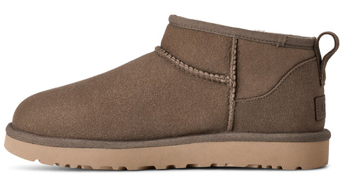 Side view of a short, taupe-colored suede boot with a tan sole and a loop on the back.
