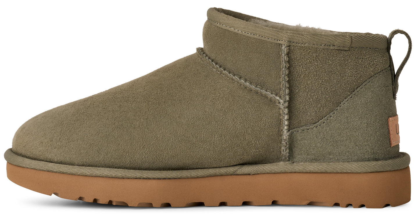 Ankle height, light green suede boot with brown sole and fabric loop on the heel.