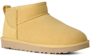 A yellow suede ankle boot with a pull tab at the back and a flat, light tan rubber sole.