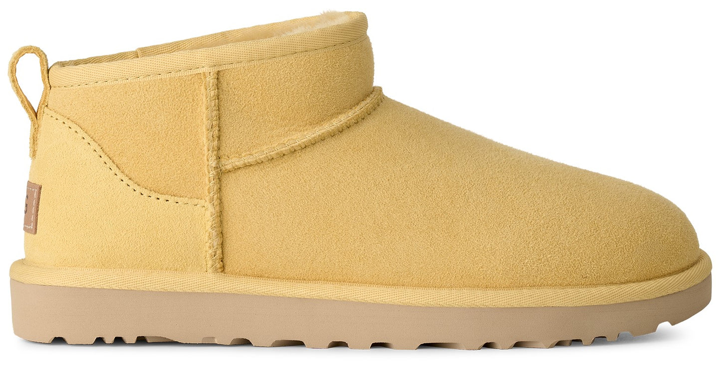 A yellow suede ankle boot with a beige rubber sole and a small pull tab on the heel.