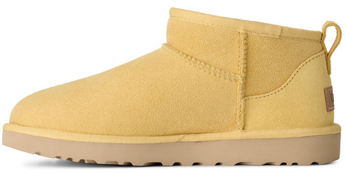 A light yellow suede ankle boot with a flat, light brown rubber outsole and a small heel tab.