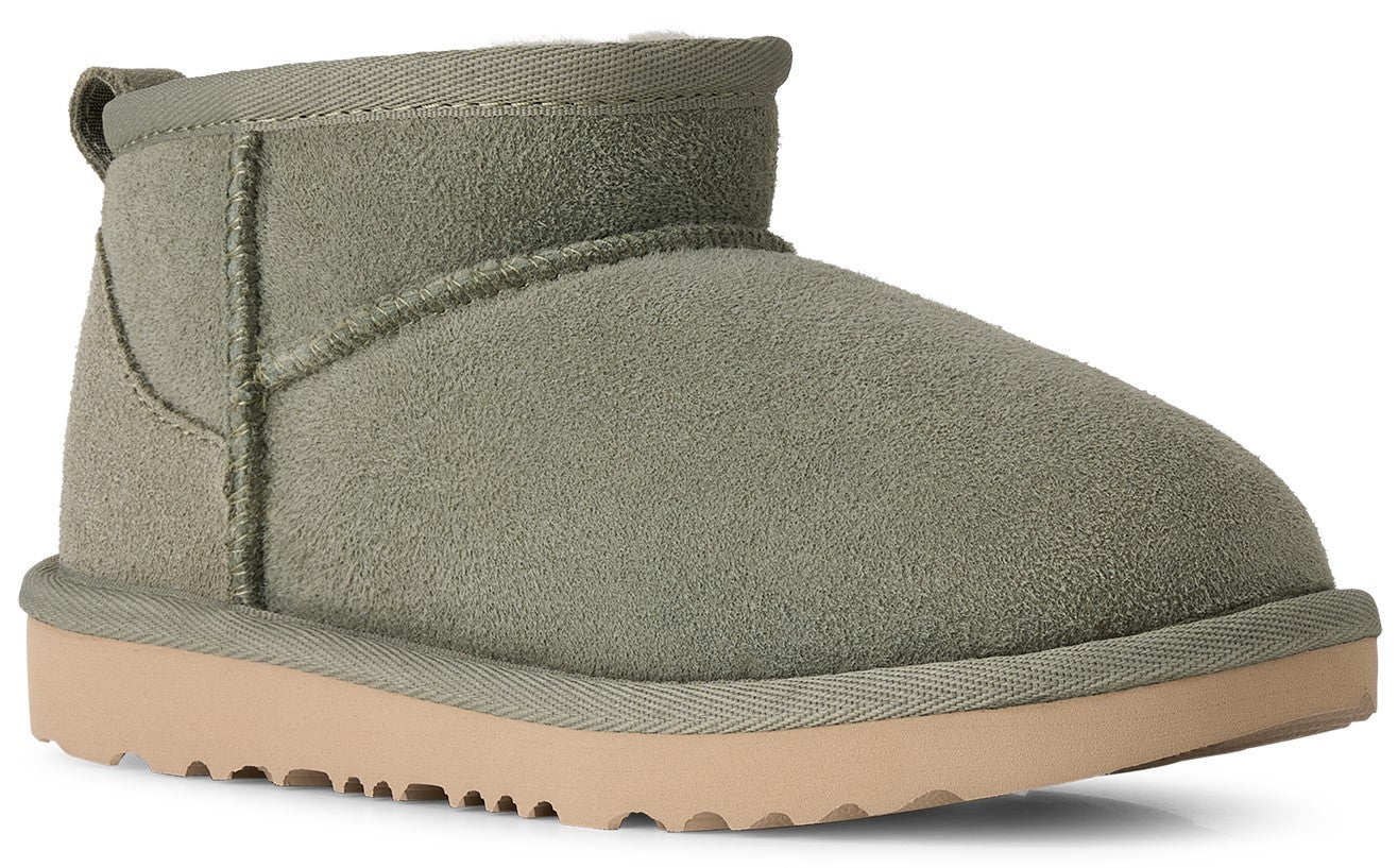 A sage green suede ankle-height winter boot with a thick light tan rubber sole and a heel pull tab.