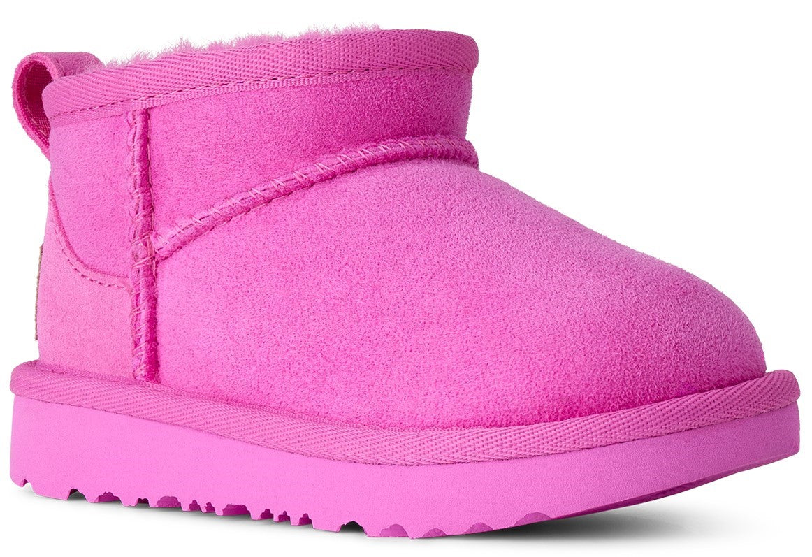 A bright pink, suede, ankle-high slip-on boot with a thick matching pink rubber sole and a plush interior lining.