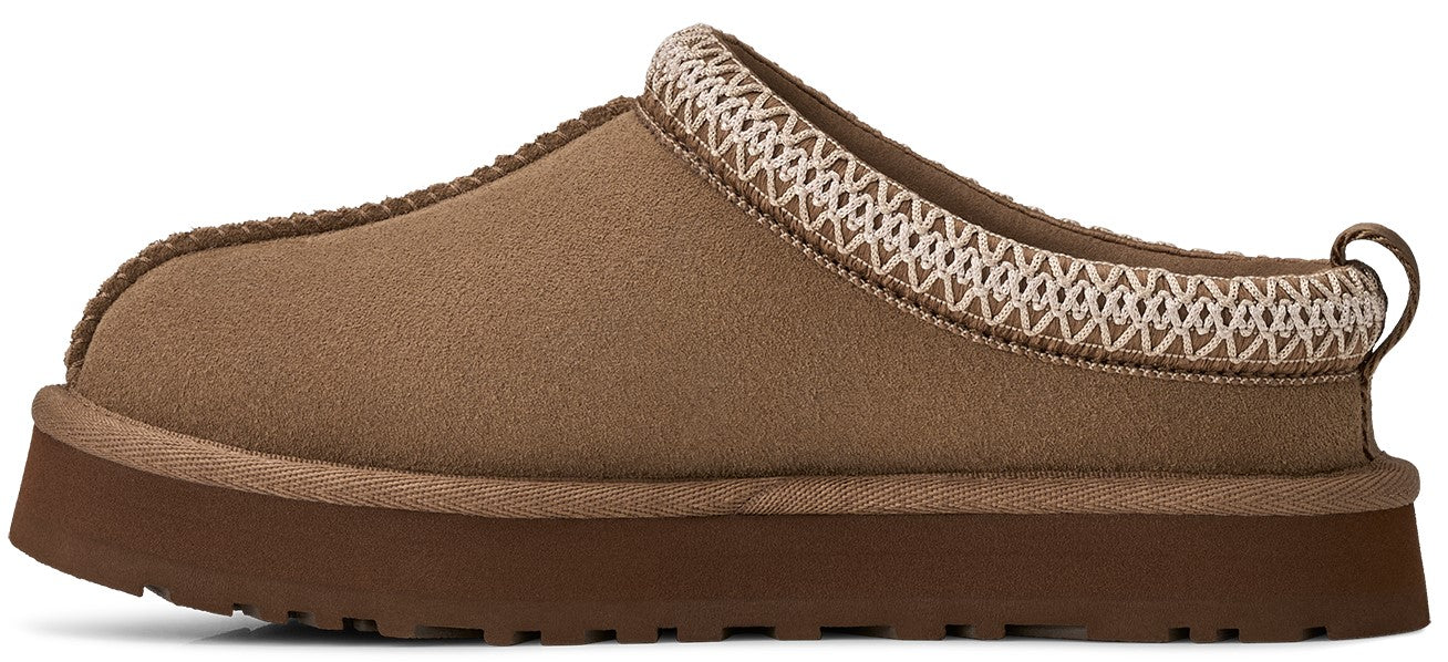 A brown, slip-on suede mule-style shoe with a thick, flat brown rubber platform sole and a decorative woven trim around the collar, shown in profile.