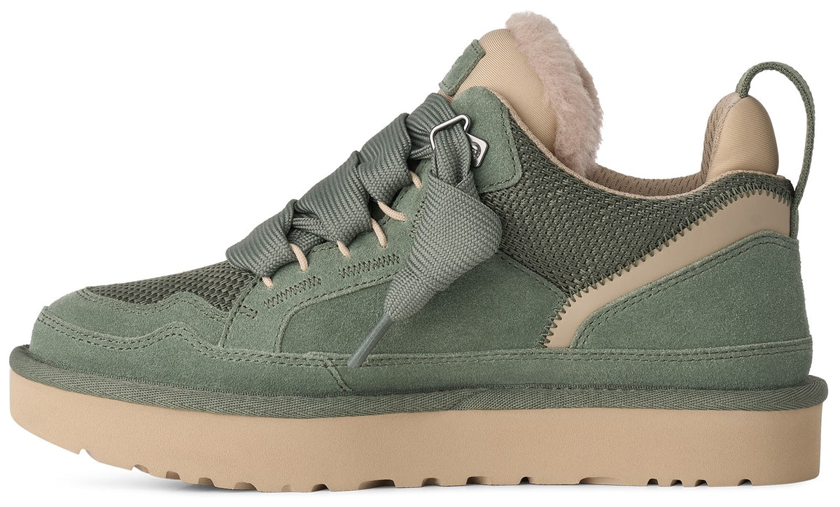 A side view of a sage green suede and mesh sneaker with a thick beige platform sole, featuring wide green laces, a soft beige faux-fur collar, and a matching heel tab.