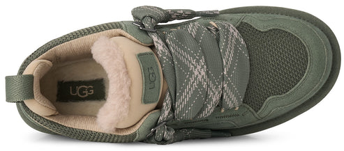 An olive green sneaker from a top-down perspective, featuring thick patterned laces, a beige plush lining around the collar, and an UGG logo patch on the tongue and inner sole.