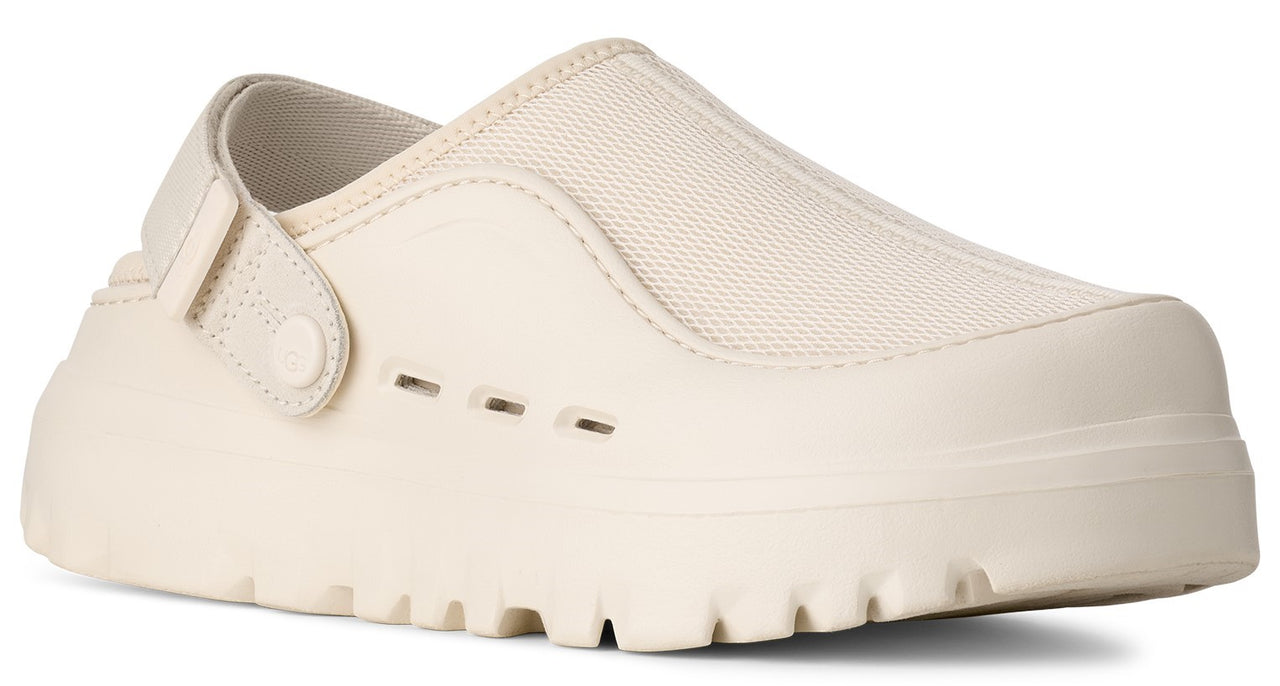 A beige colored clog with a textured sole.