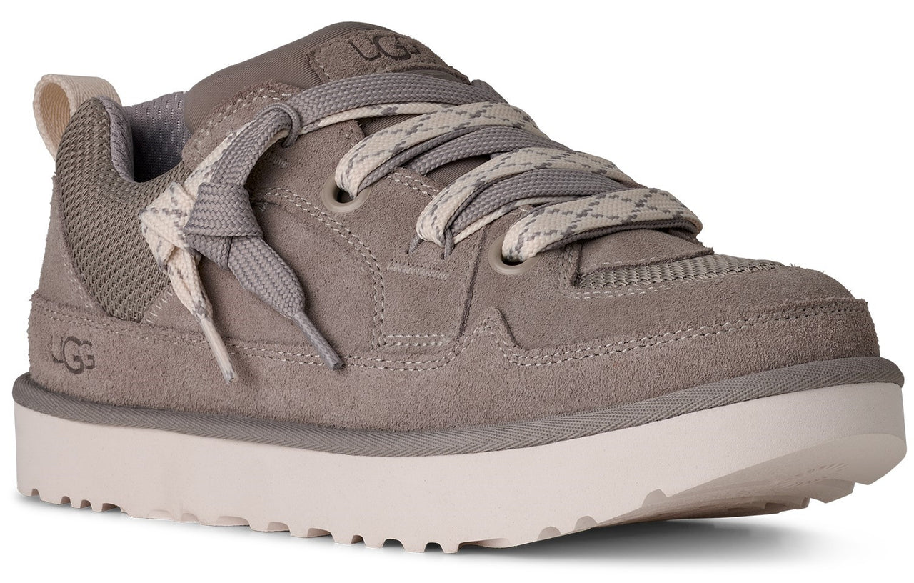 A gray sneaker with gray laces, off-white sole, gray mesh padding around ankle, and "UGG" logo on side.