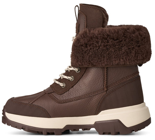 A brown leather ankle winter boot with a thick cream-colored rubber sole, a dark brown faux-fur cuff, and cream-and-brown speckled laces.