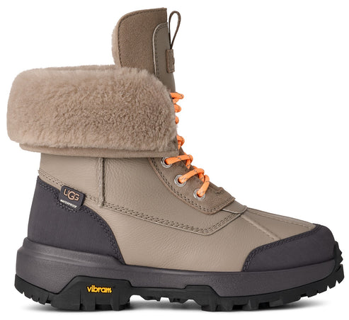 High cut boot in tan leather with gray rubber trim, orange laces, and shearling-style fold-over top.