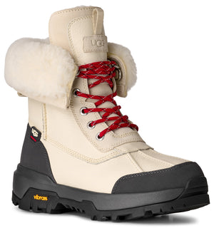 Beige boot with white furry trim, red laces, silver eyelets, and a chunky black sole.
