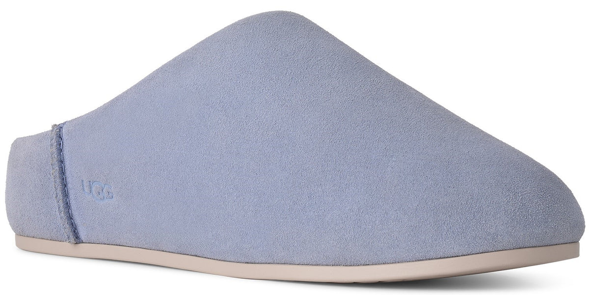 A light periwinkle suede slip-on shoe with a flat, beige sole and the word UGG embossed on the side heel.