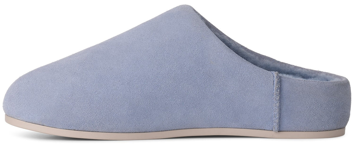 A light blue suede mule-style slipper with a flat, light beige sole and a soft, plush-lined interior.