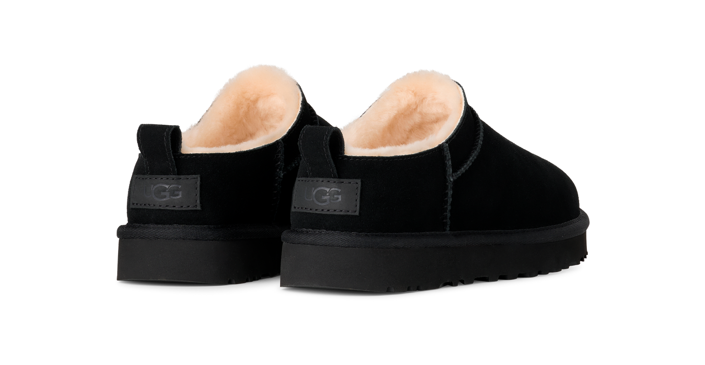 A pair of black suede scuff slippers with shearling linings, and platform soles.