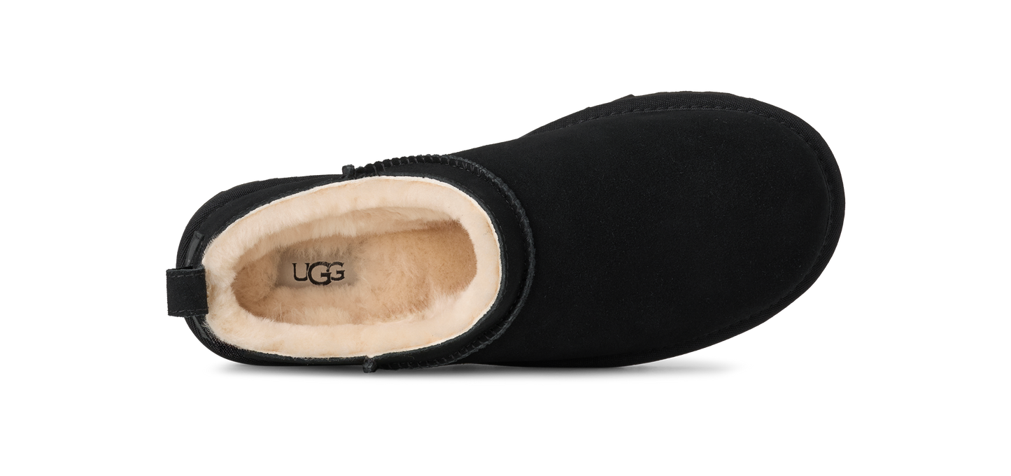 Close-up of an UGG boot, black with a cream-colored interior, showing the brand UGG inside.