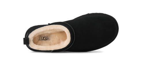 Close-up of an UGG boot, black with a cream-colored interior, showing the brand UGG inside.