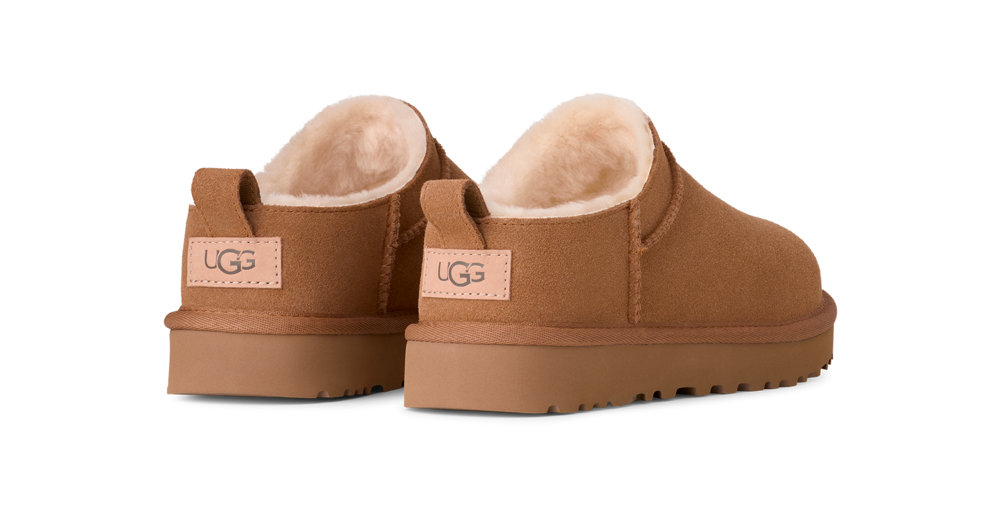 A pair of chestnut-colored UGG slippers with a visible label on the heel.