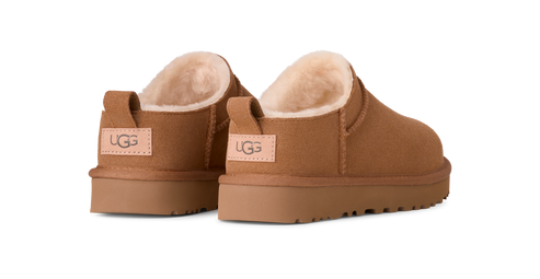 A pair of chestnut-colored UGG slippers with a visible label on the heel.