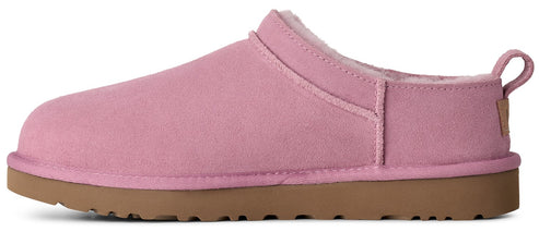 A pink suede slip-on shoe with a thick brown rubber sole, featuring a fur-lined interior and a small pull tab at the heel.