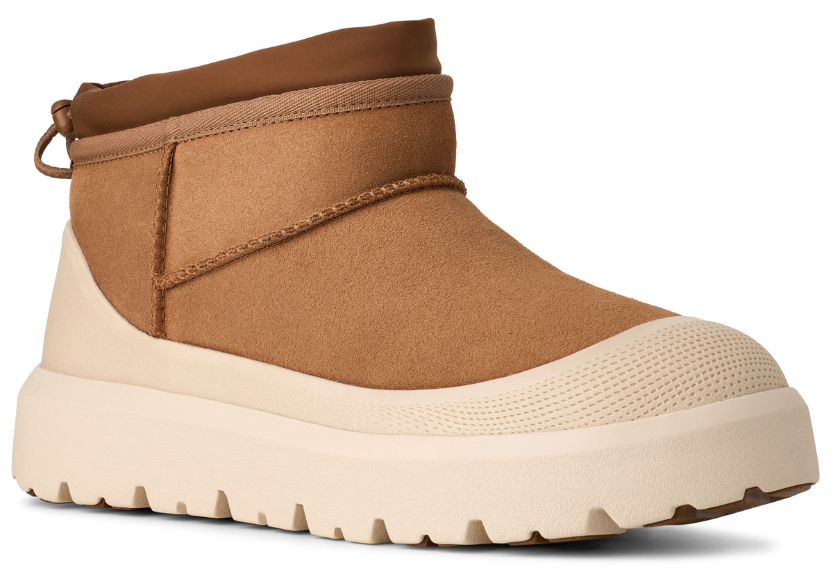 A tan suede ankle boot featuring a thick, off-white textured rubber sole with a molded toe cap and a pull tab at the back collar.