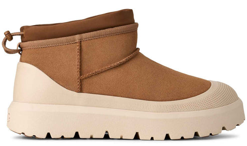 A tan suede ankle boot with a high, thick, cream-colored rubber lug sole that wraps around the base, featuring a toggle adjustment at the back.