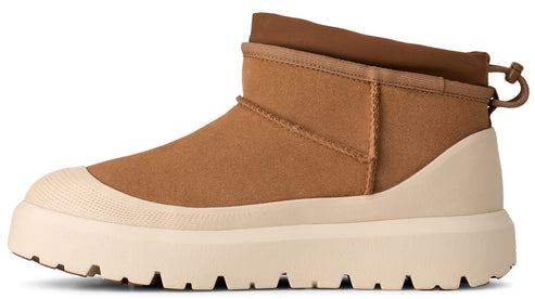 A tan suede ankle boot with a high-profile, cream-colored, ridged platform lug sole and a pull-toggle at the back heel.